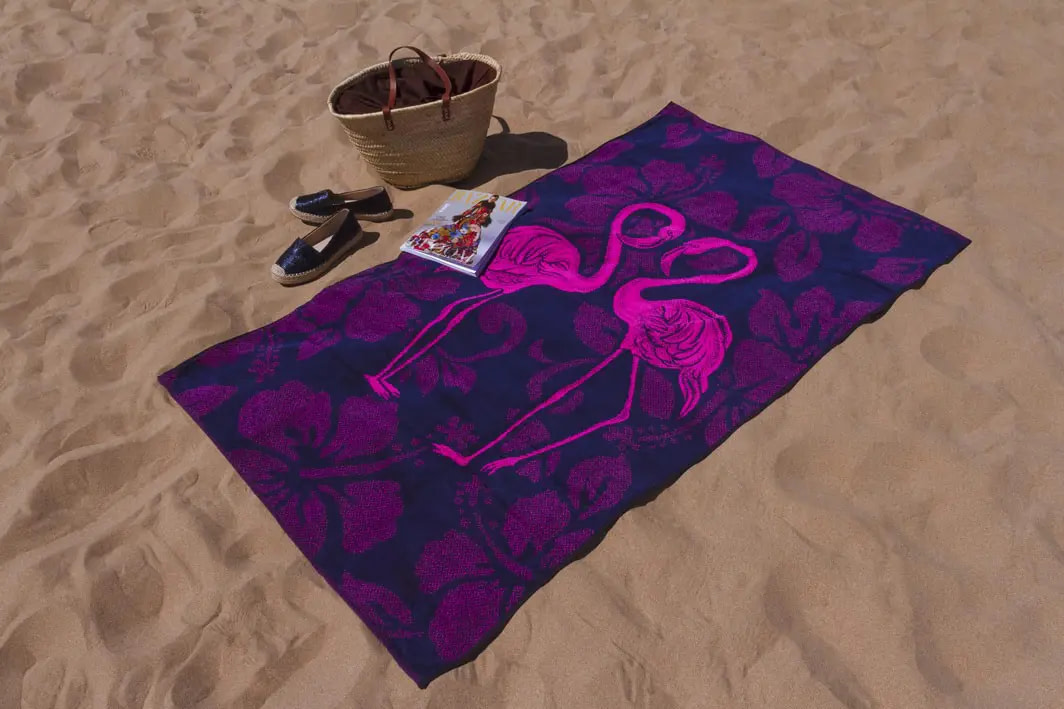 display de la toalla de playa de flamencos lila extendida en la playa