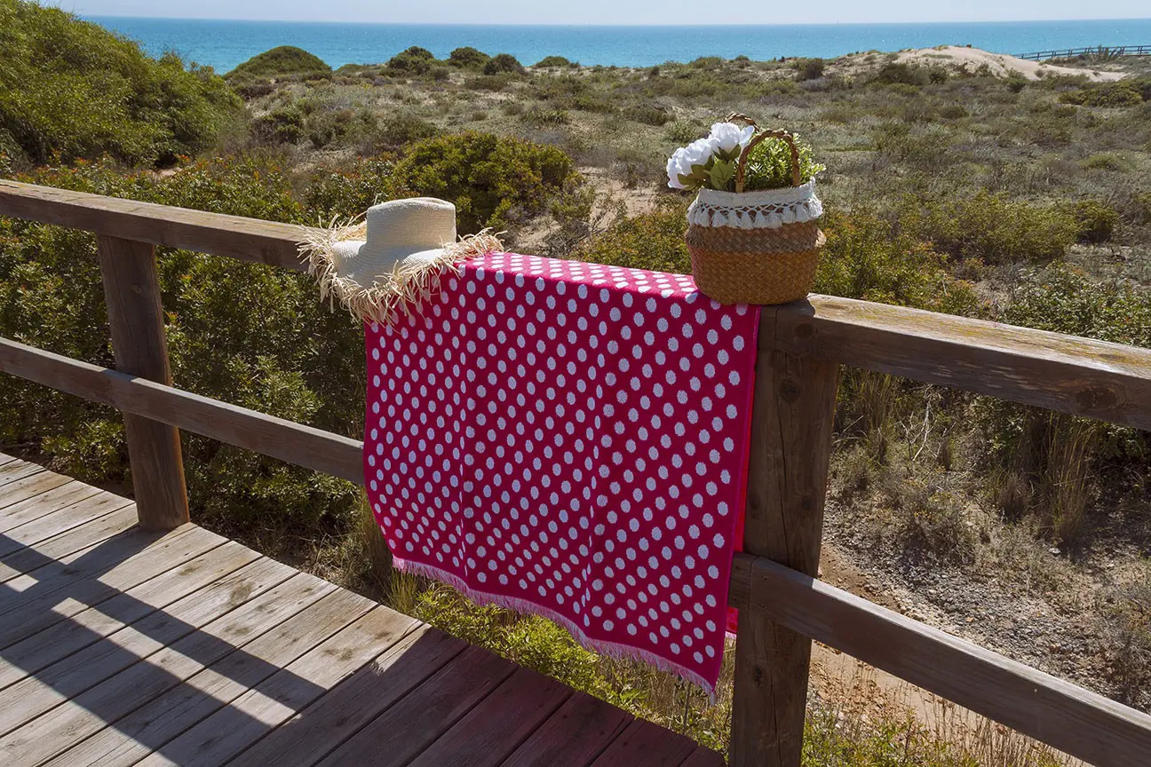 toalla de playa rosa con lunares y flecos en la playa