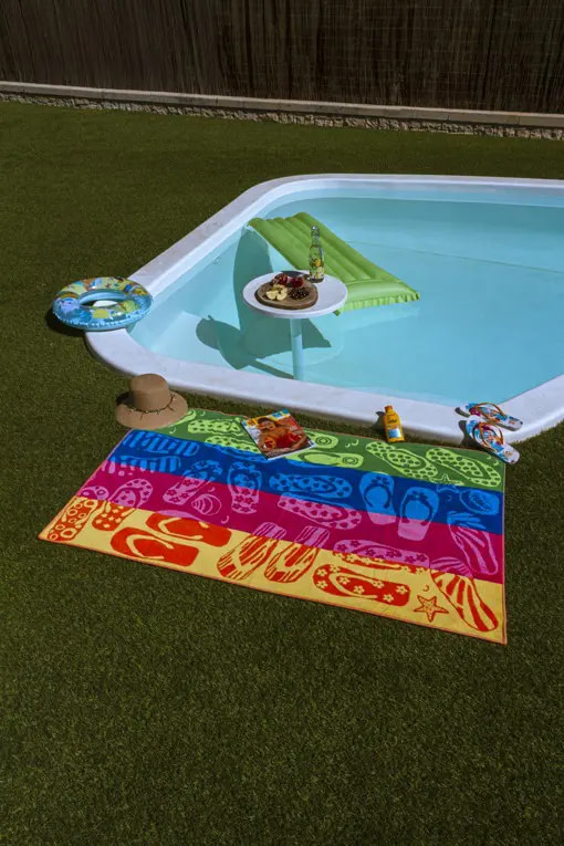 display de la toalla de playa chanclas sobre el cesped de la piscina