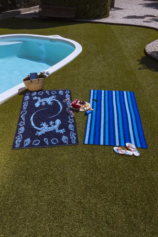 toallas de playa de tonos azules en el cesped de la piscina
